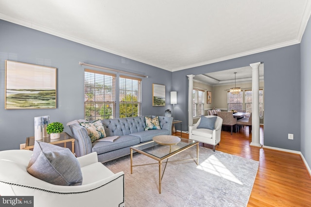 living room featuring crown molding, baseboards, decorative columns, an inviting chandelier, and wood finished floors