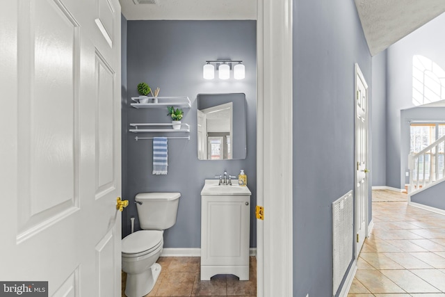 half bath with tile patterned floors, toilet, vanity, and baseboards