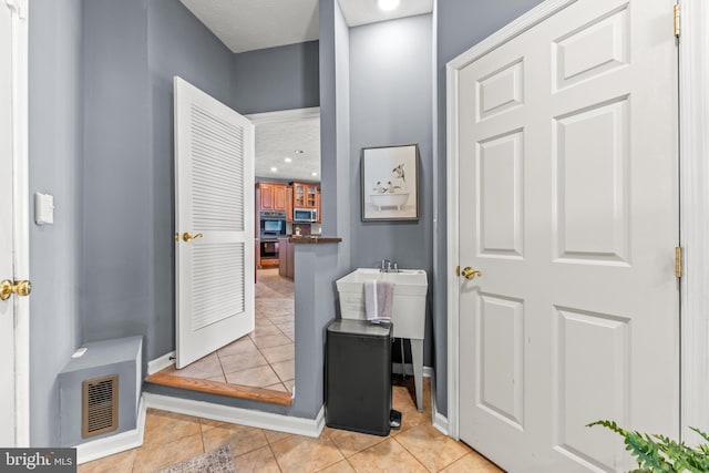 bathroom featuring tile patterned floors, visible vents, a textured ceiling, and baseboards
