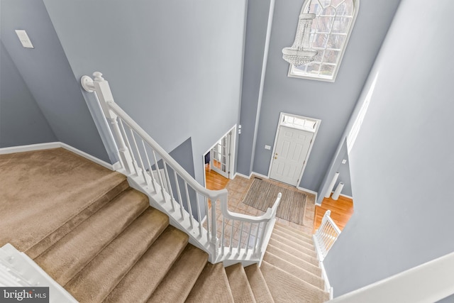 stairway featuring a high ceiling and baseboards
