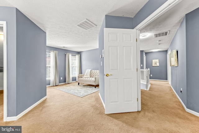unfurnished room featuring an upstairs landing, visible vents, carpet floors, and baseboards