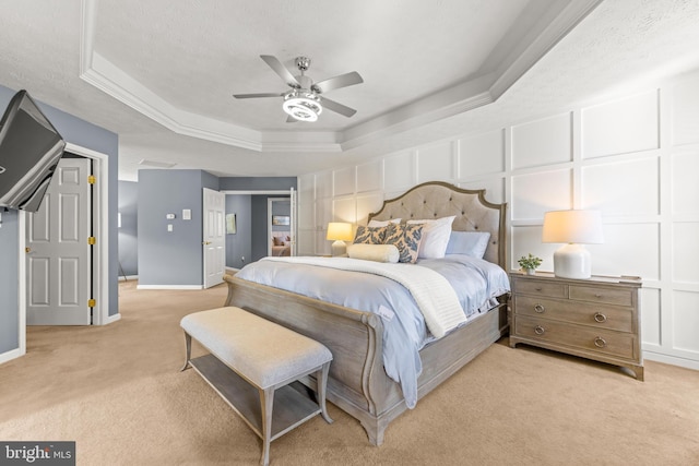 bedroom with baseboards, a textured ceiling, a raised ceiling, a decorative wall, and light colored carpet