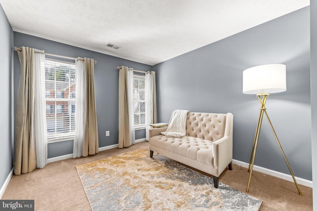 sitting room with carpet flooring, baseboards, visible vents, and a textured ceiling