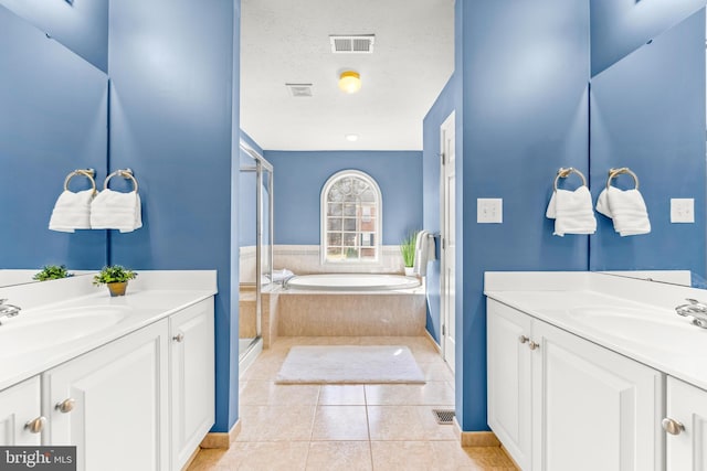 full bath featuring tile patterned flooring, two vanities, visible vents, and a textured ceiling
