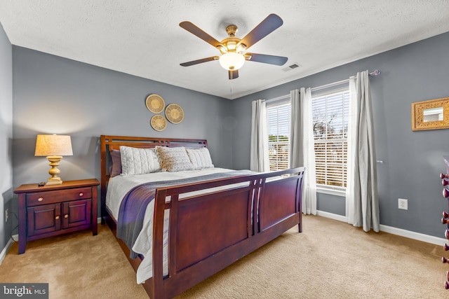 carpeted bedroom with visible vents, baseboards, a textured ceiling, and a ceiling fan
