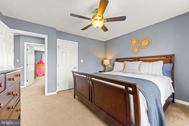 bedroom featuring light carpet, ceiling fan, a textured ceiling, and baseboards
