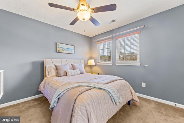 carpeted bedroom featuring visible vents, baseboards, and ceiling fan