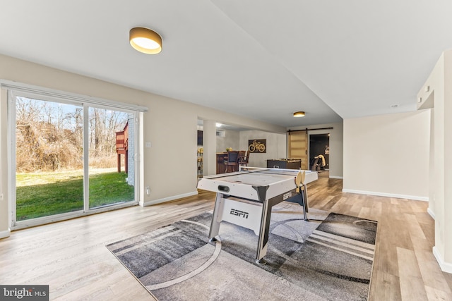 recreation room with a barn door, wood finished floors, and baseboards