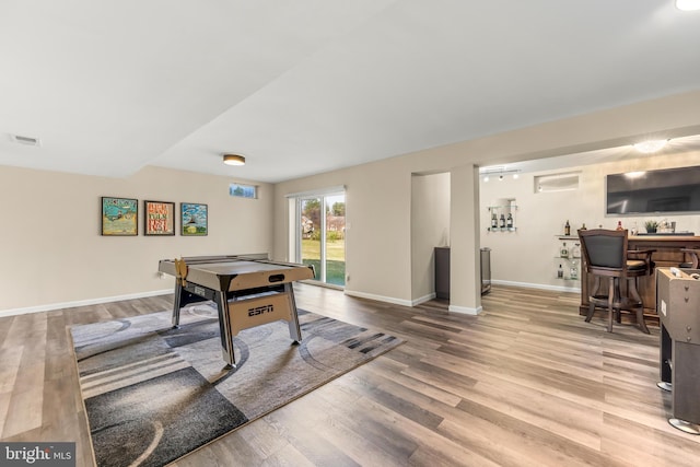 game room featuring bar, wood finished floors, visible vents, and baseboards