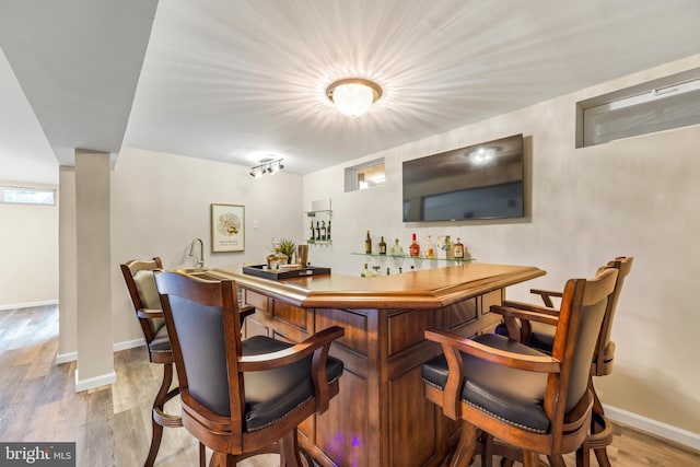 bar with indoor wet bar, baseboards, and wood finished floors