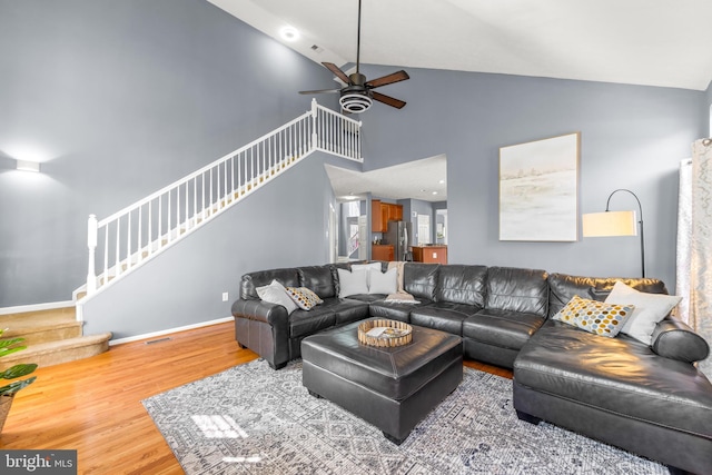 living room with stairway, wood finished floors, baseboards, high vaulted ceiling, and ceiling fan