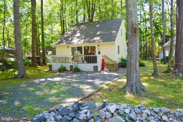 back of property featuring a yard, roof with shingles, and a deck