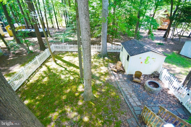 view of yard with a storage shed, a fenced backyard, an outbuilding, and an outdoor fire pit