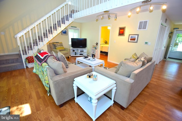 living room featuring a wealth of natural light, stairway, visible vents, and wood finished floors