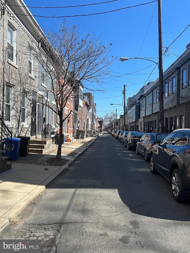 view of road featuring street lights, sidewalks, curbs, and a residential view