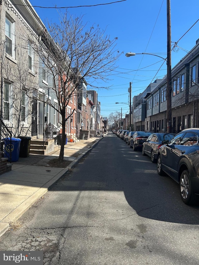 view of street featuring sidewalks, curbs, a residential view, and street lighting