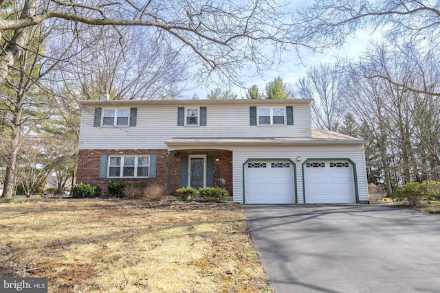 traditional-style house with brick siding, driveway, a chimney, and a garage