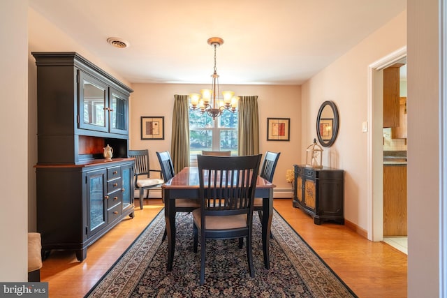 dining room featuring visible vents, a baseboard heating unit, light wood finished floors, baseboard heating, and a chandelier