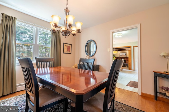 dining space with an inviting chandelier, light wood-style floors, baseboards, and baseboard heating