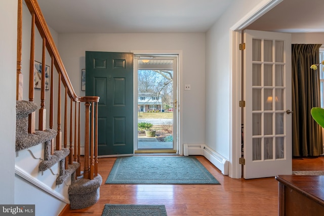 foyer featuring stairs, a baseboard heating unit, and wood finished floors