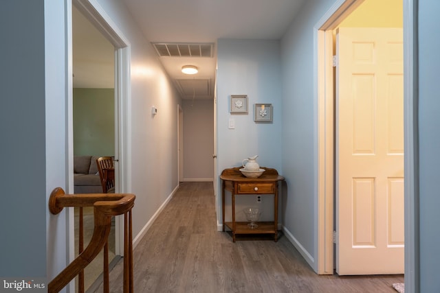 hallway with visible vents, attic access, baseboards, and wood finished floors