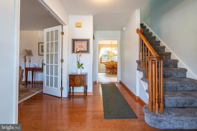 entryway featuring stairway, baseboards, wood finished floors, and a baseboard heating unit