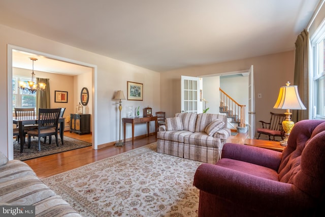 living room featuring a wealth of natural light, a chandelier, wood finished floors, and stairs