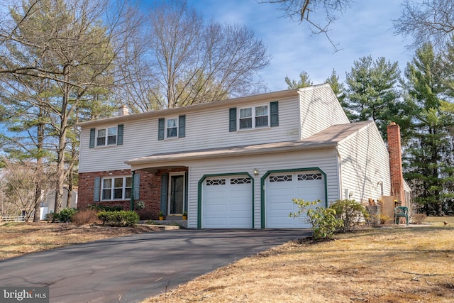 traditional-style house with a garage, brick siding, driveway, and a chimney