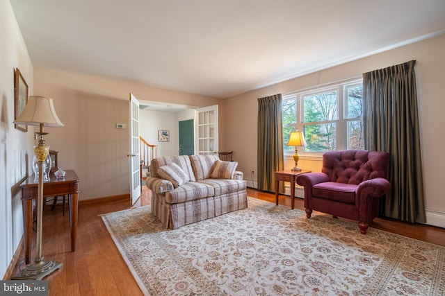 living room featuring baseboards, wood finished floors, and stairs