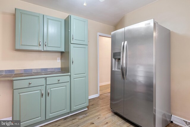 kitchen featuring visible vents, light wood-style flooring, stainless steel refrigerator with ice dispenser, tile countertops, and baseboards