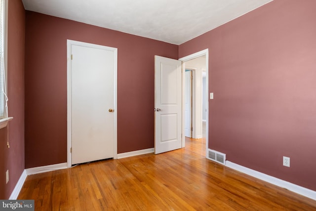 unfurnished bedroom featuring wood finished floors, visible vents, and baseboards