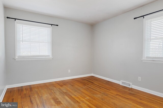 spare room with visible vents, baseboards, and hardwood / wood-style floors