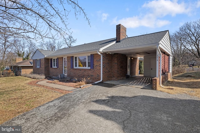 ranch-style house with driveway, a shingled roof, a chimney, a front lawn, and brick siding