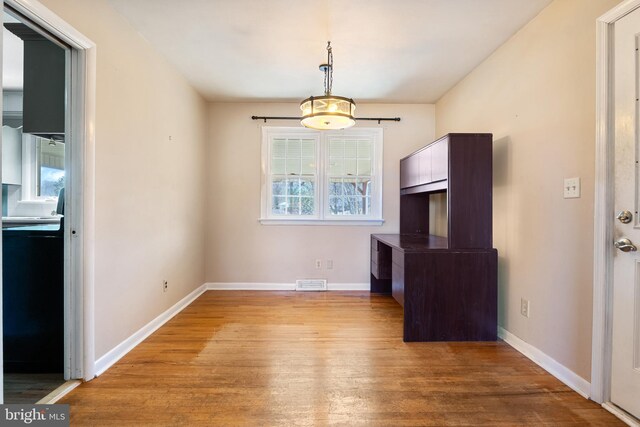 unfurnished dining area with wood finished floors, visible vents, and baseboards