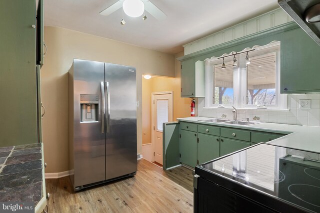 kitchen with green cabinetry, electric range, a sink, stainless steel fridge, and tasteful backsplash