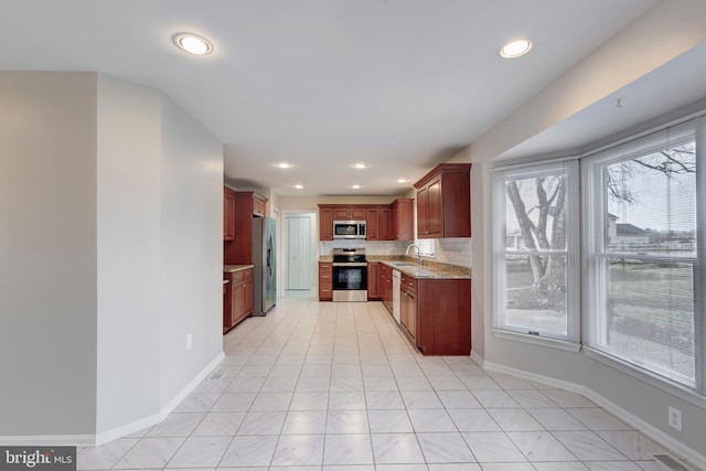 kitchen with light stone counters, baseboards, recessed lighting, a sink, and stainless steel appliances