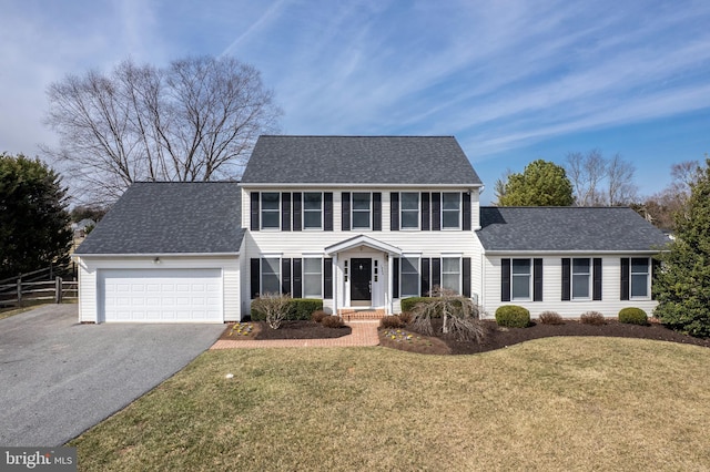 colonial-style house with aphalt driveway, a garage, a front yard, and fence