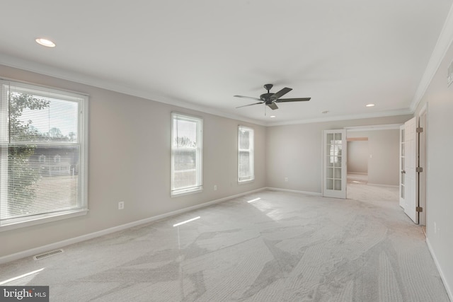 empty room with light colored carpet, visible vents, baseboards, and ornamental molding