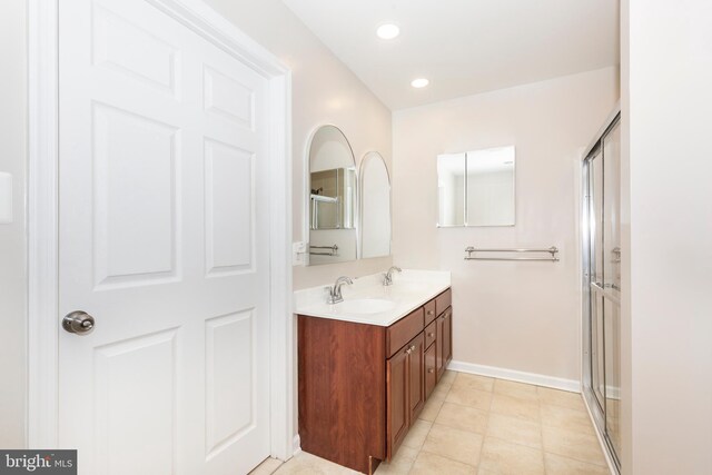 full bath with double vanity, an enclosed shower, and a sink