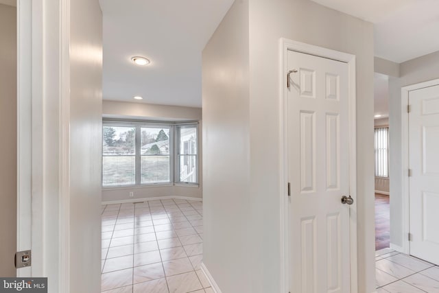 hall featuring light tile patterned flooring and baseboards