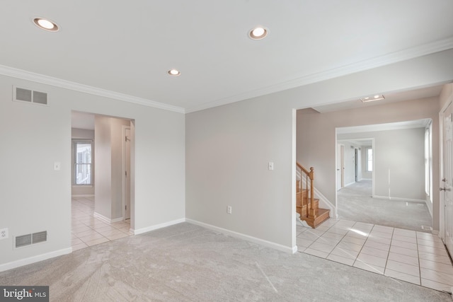 tiled spare room with visible vents, ornamental molding, and carpet floors