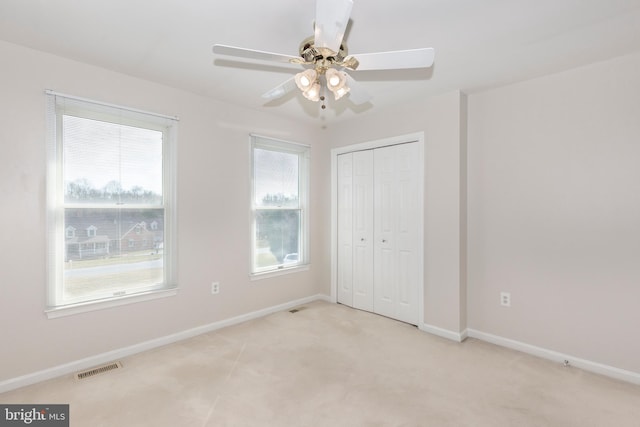 unfurnished bedroom featuring baseboards, visible vents, multiple windows, and a closet