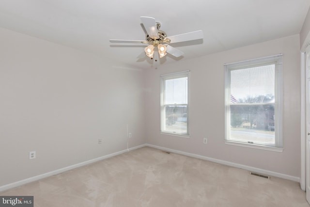 unfurnished room with visible vents, baseboards, light colored carpet, and a ceiling fan