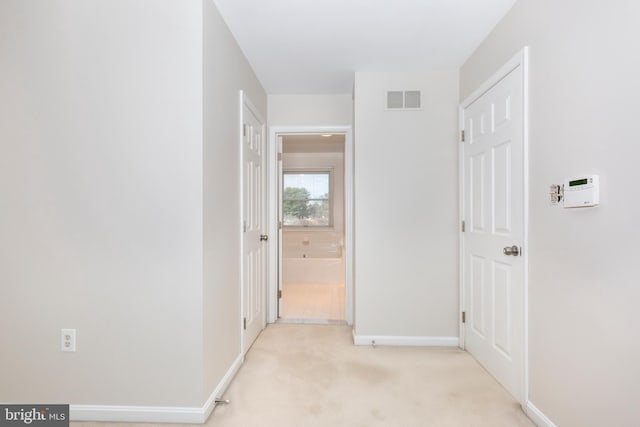 corridor with visible vents, light carpet, and baseboards