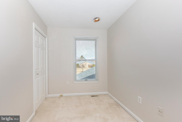 unfurnished room with visible vents, baseboards, and light carpet