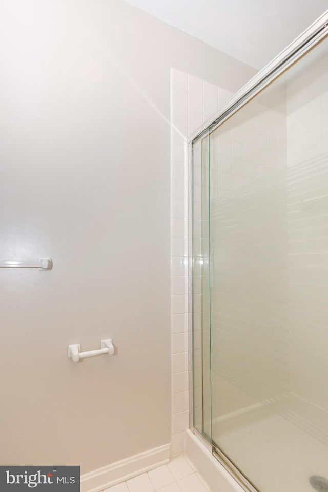 bathroom with tile patterned floors, baseboards, and a shower stall