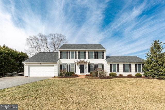 colonial inspired home featuring an attached garage, a front lawn, fence, roof with shingles, and driveway