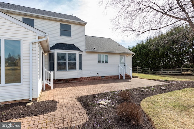 rear view of house with fence, roof with shingles, entry steps, crawl space, and a patio area