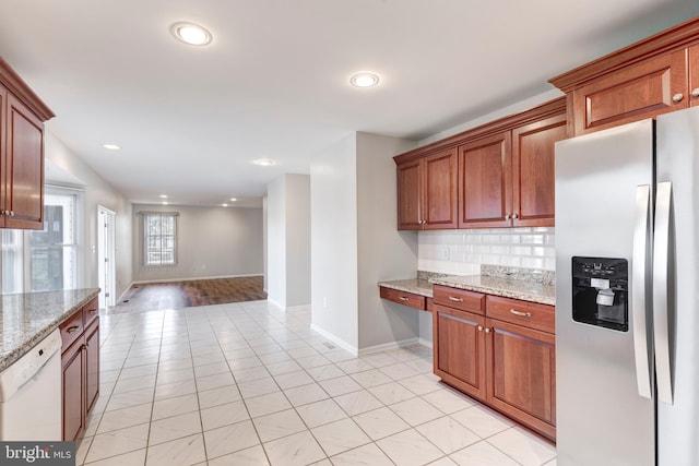 kitchen with baseboards, stainless steel fridge with ice dispenser, light stone counters, decorative backsplash, and white dishwasher