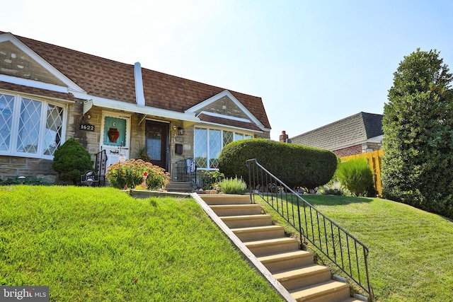 view of front of property with mansard roof, stone siding, and roof with shingles